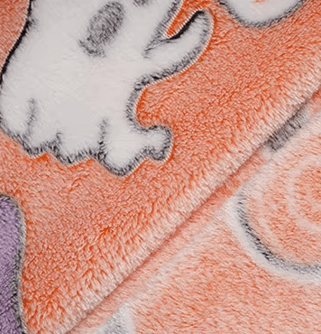 Zoomed view of glowing ghost and pumpkin print on plush Halloween fabric