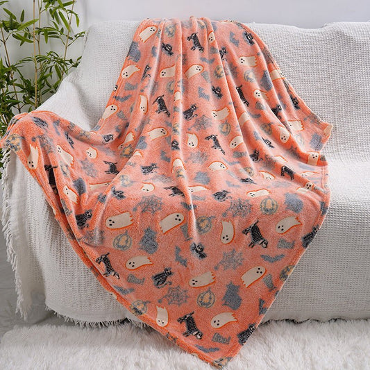 Glowing Halloween blanket (ghosts & pumpkins) draped over sofa, plush sherpa fleece
