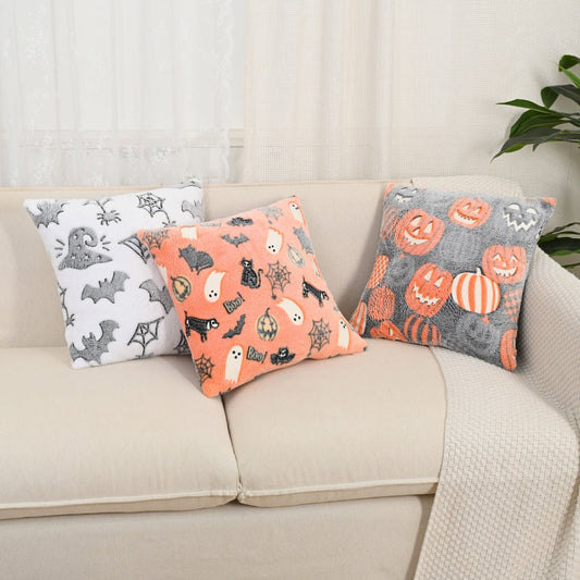 Three 18×18 glow-in-the-dark Halloween pillows (ghost, pumpkin, bat motifs) on a couch
